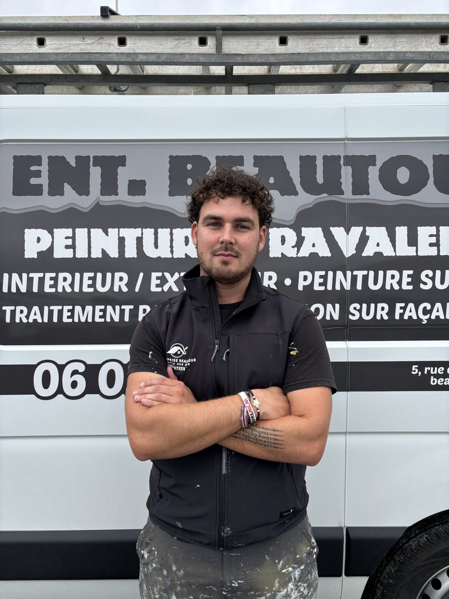 Edjy, artisan, en gilet de travail et bras croisés devant le camion Ent. Beautour
